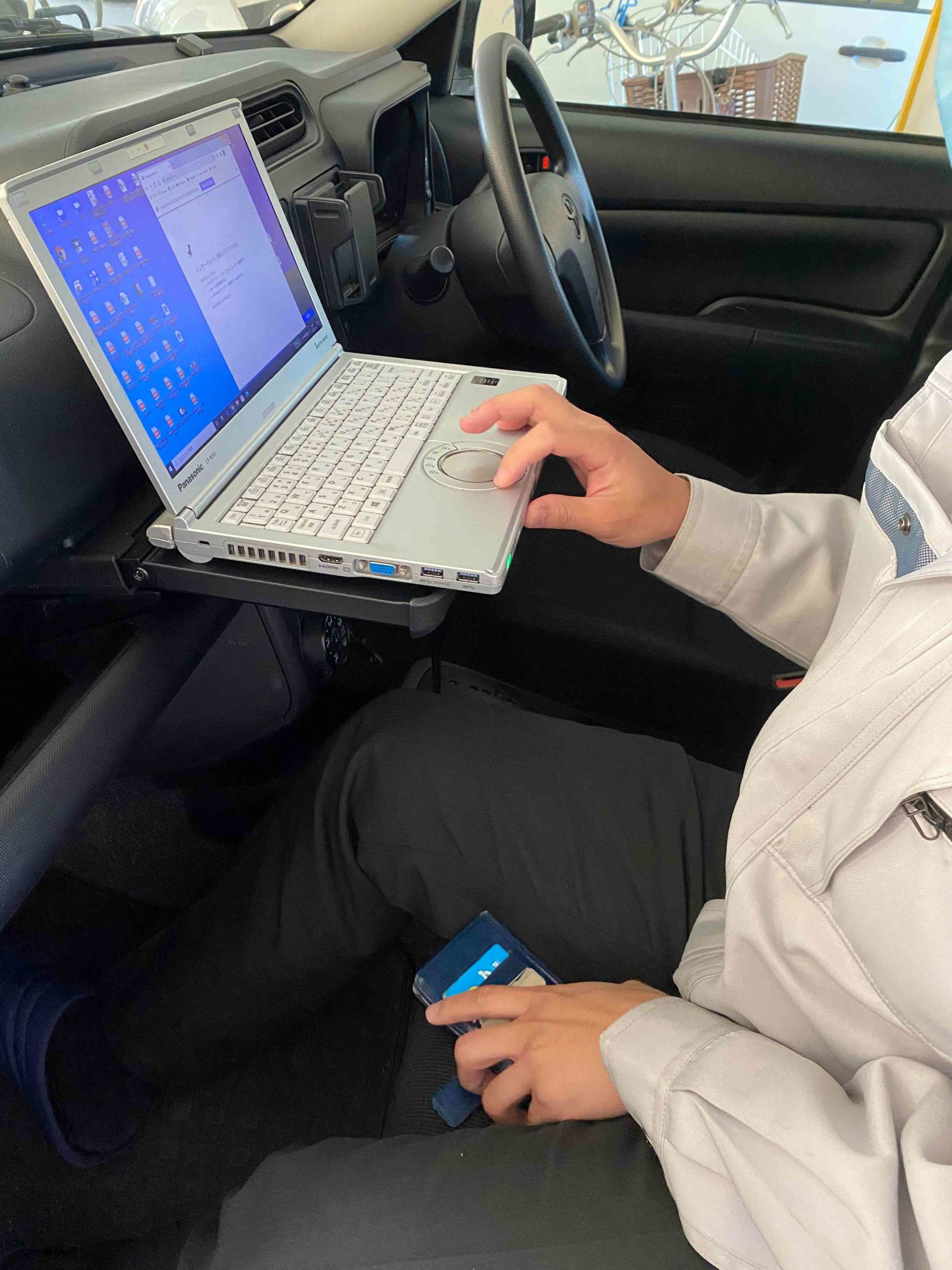車内の助手席にあるテーブルでレンタルPCを使っているシーン
